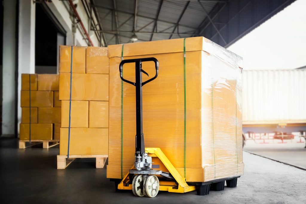 Paleteira hidráulica manual carregando caixas na logística de armazenagem